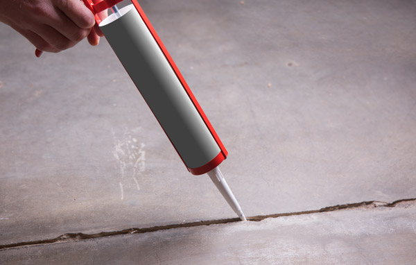 Appling caulk to concrete floor