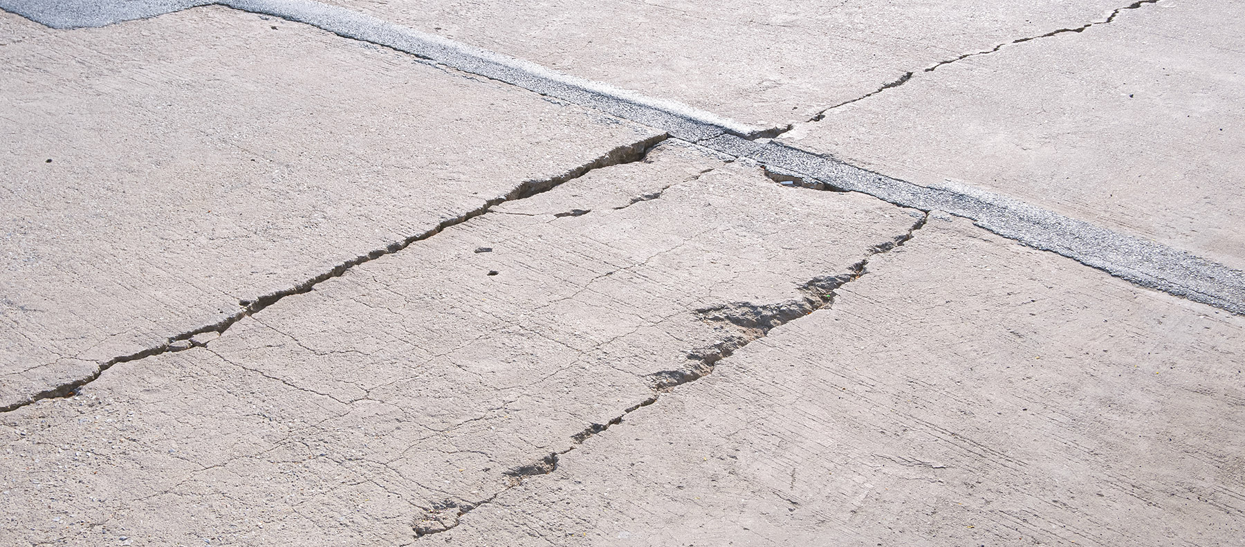 Photo of a cracked driveway in need of leveling, patching, and resurfacing