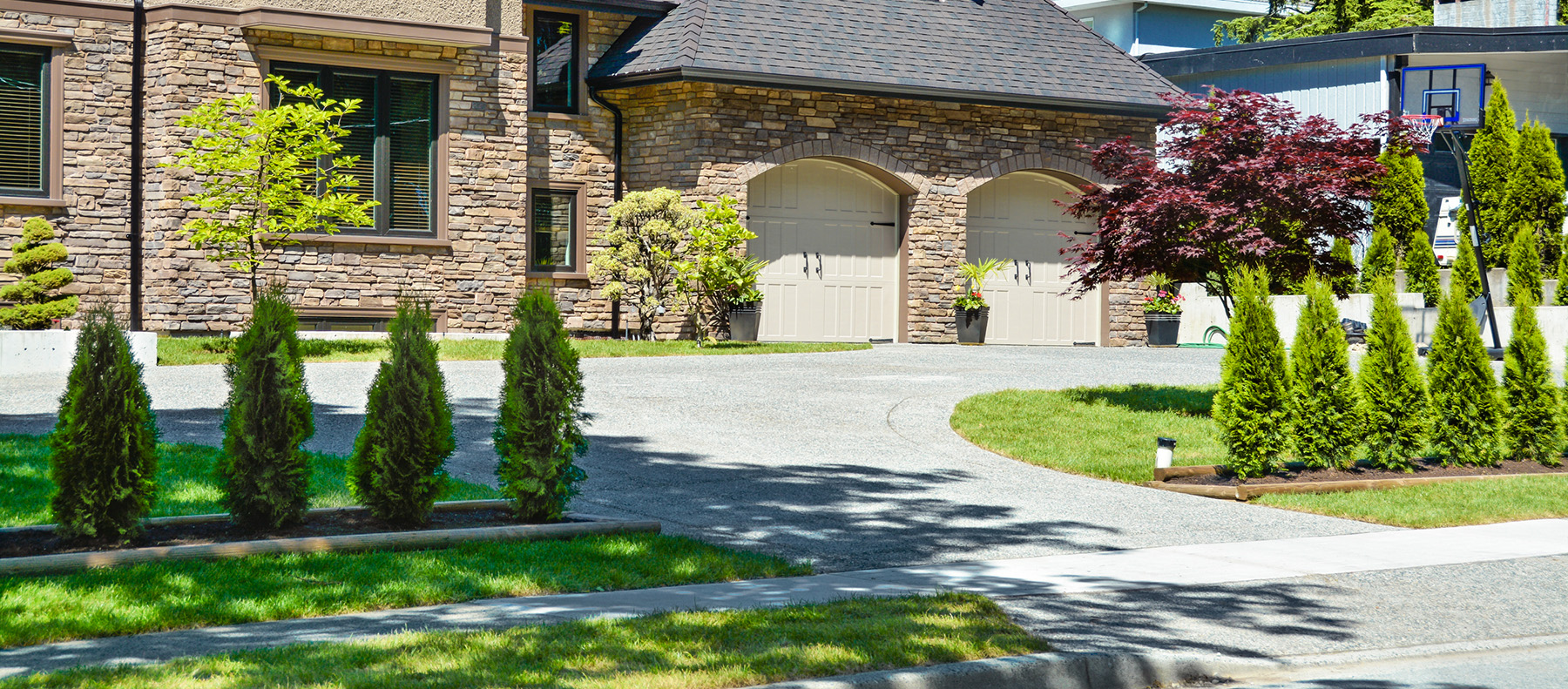 Photo of a concrete driveway and sidewalk in front of a nice residential home